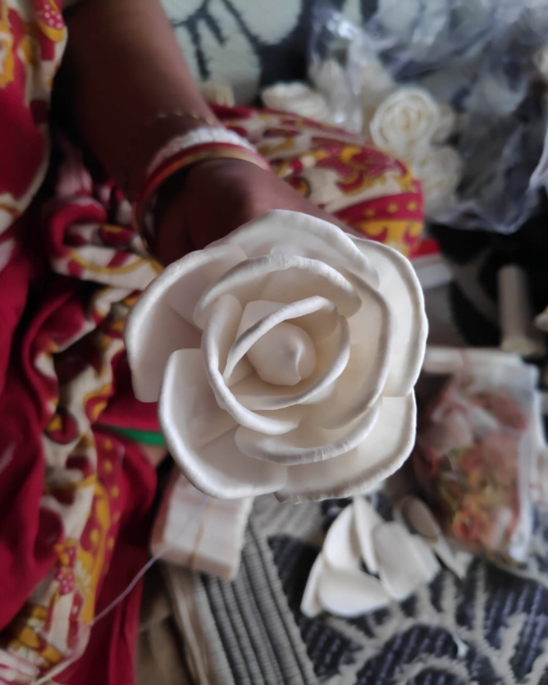 Close-up of a hand-crafted white sola flower being assembled from thin wood-like shola plant sheets.