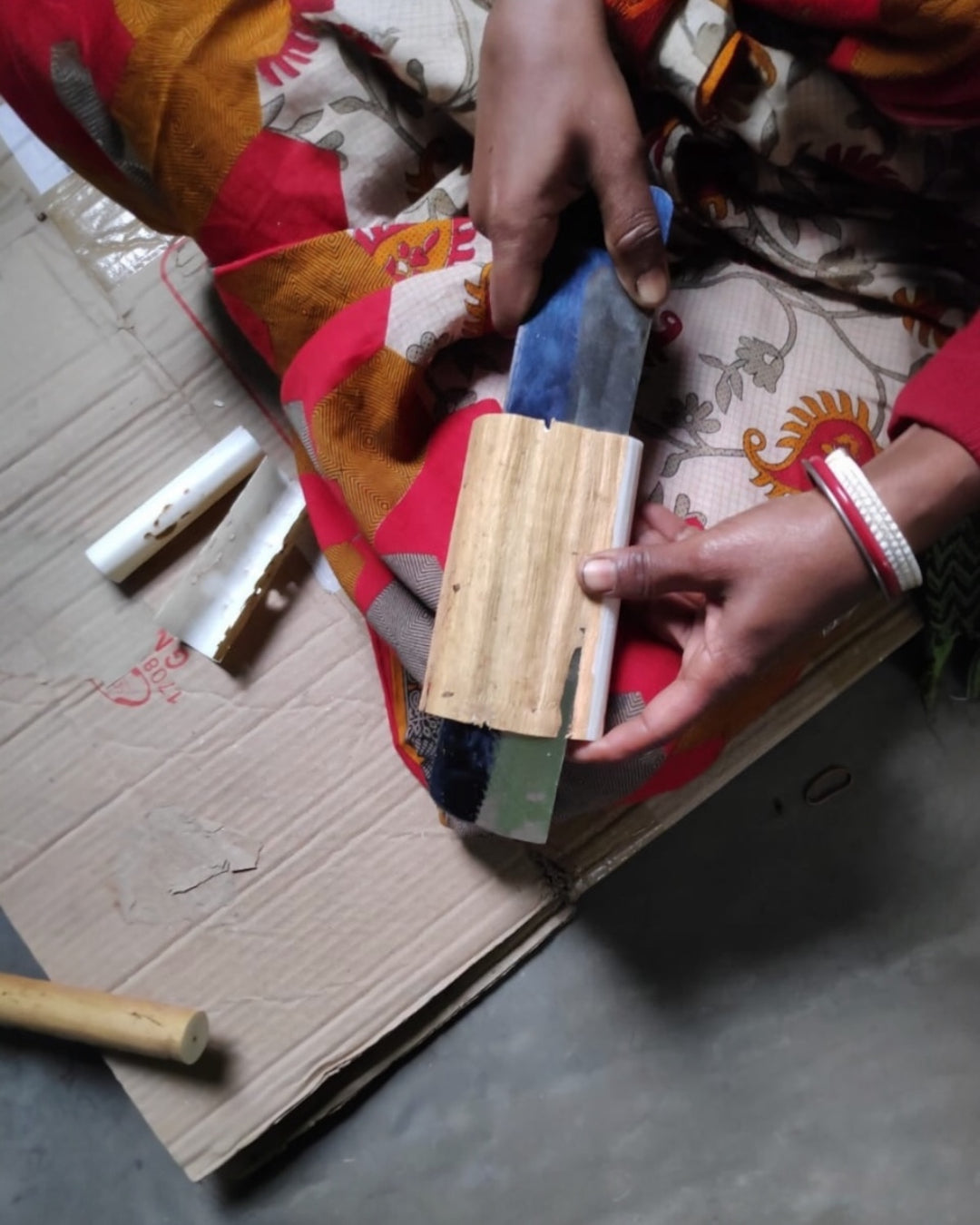 Hands carefully peeling the outer bark of a shola plant stalk to reveal the white pith used for sola flowers.